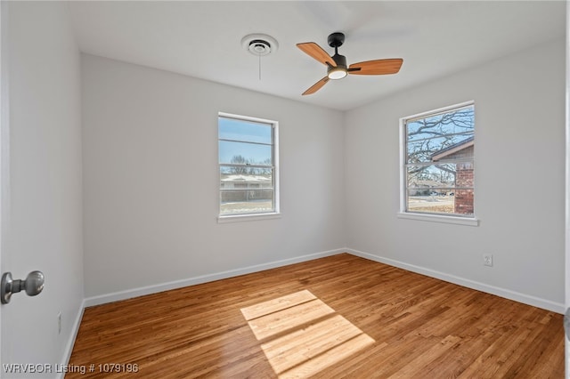 spare room featuring a healthy amount of sunlight, visible vents, baseboards, and wood finished floors