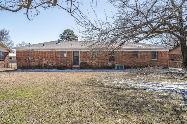 rear view of house with brick siding, a lawn, and central AC unit