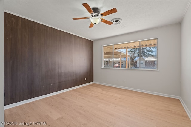 spare room featuring visible vents, light wood-style flooring, ceiling fan, a textured ceiling, and baseboards