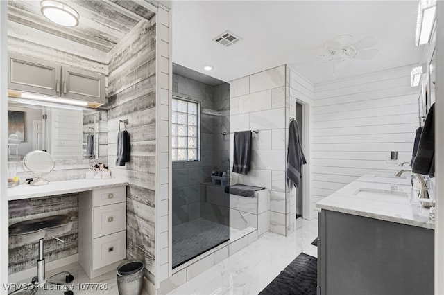 bathroom featuring a tile shower, vanity, ceiling fan, and wooden walls