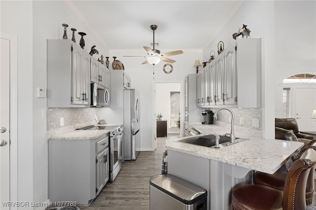 kitchen featuring ceiling fan, sink, kitchen peninsula, decorative backsplash, and appliances with stainless steel finishes