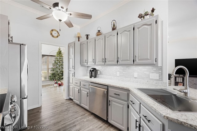 kitchen with backsplash, ornamental molding, sink, and appliances with stainless steel finishes