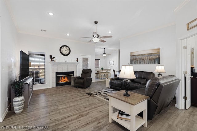 living room with a fireplace, hardwood / wood-style flooring, ceiling fan, and ornamental molding