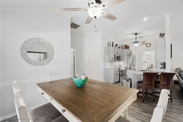 dining area featuring sink, ornamental molding, and light wood-type flooring