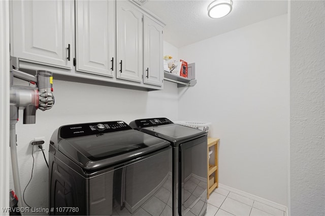 laundry room with light tile patterned flooring, cabinets, separate washer and dryer, and a textured ceiling