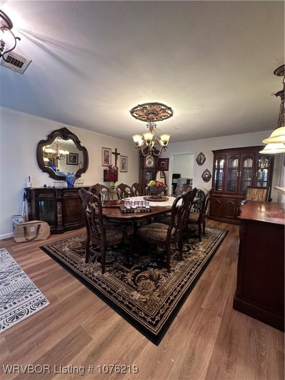 dining space featuring wood-type flooring and an inviting chandelier