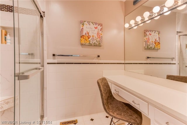 bathroom featuring tile patterned flooring, vanity, tile walls, and a shower with shower door