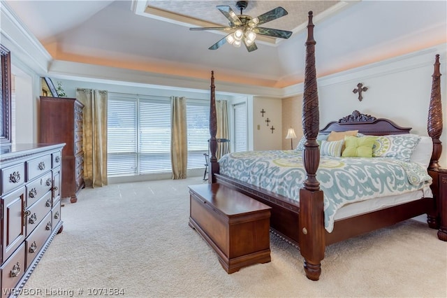 carpeted bedroom with ceiling fan, crown molding, a tray ceiling, and vaulted ceiling