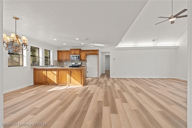 kitchen featuring open floor plan, brown cabinets, appliances with stainless steel finishes, and a peninsula