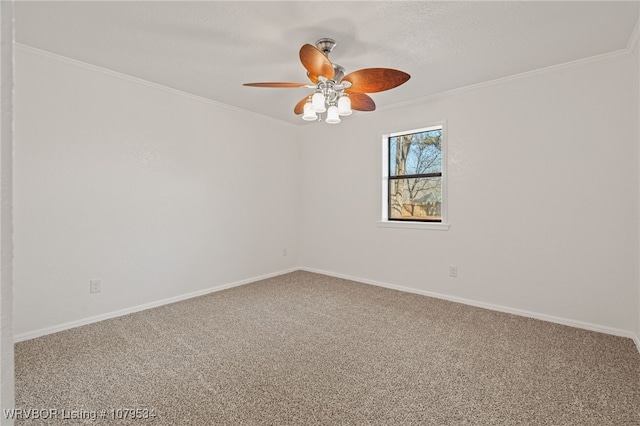 carpeted empty room with baseboards, a ceiling fan, and crown molding