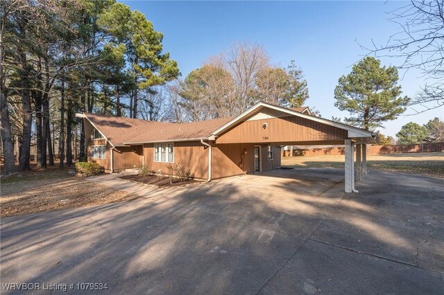 view of front of house featuring an attached carport, concrete driveway, and fence