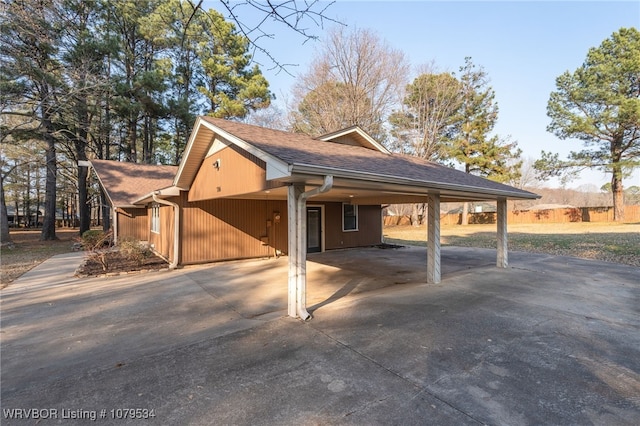 view of side of property with a carport, driveway, and a shingled roof