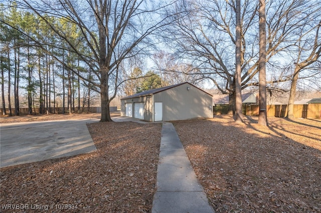 view of home's exterior featuring an outdoor structure, fence, driveway, and a detached garage