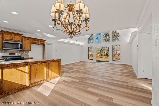 kitchen featuring brown cabinetry, stainless steel appliances, open floor plan, tasteful backsplash, and a chandelier