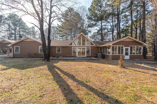 rear view of house featuring cooling unit, a lawn, and a sunroom