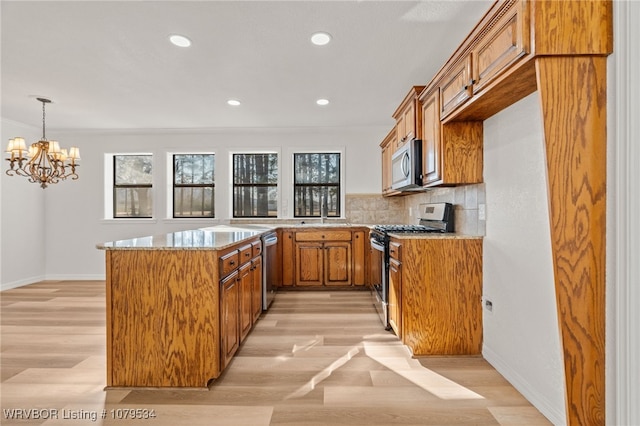 kitchen with light wood-type flooring, brown cabinets, tasteful backsplash, and appliances with stainless steel finishes