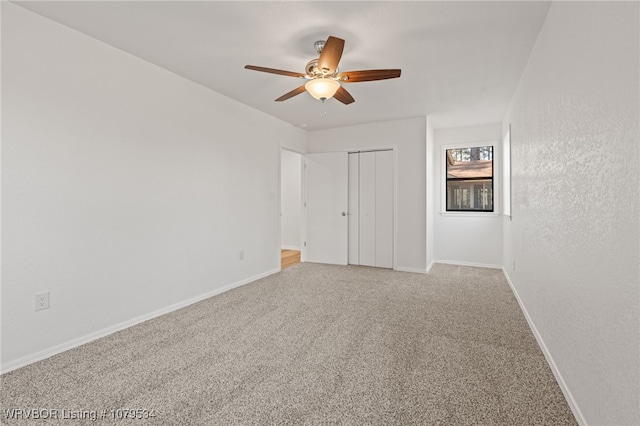 unfurnished bedroom featuring a ceiling fan, baseboards, a closet, and light carpet