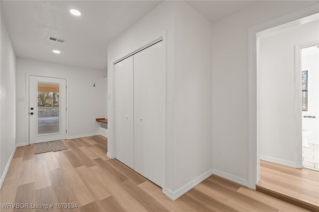 corridor featuring visible vents, baseboards, light wood-style floors, and a healthy amount of sunlight