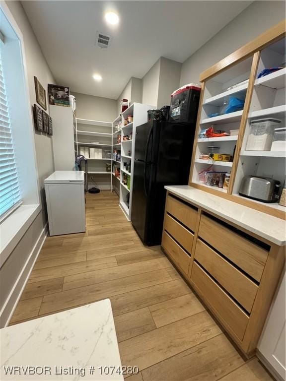 kitchen featuring light hardwood / wood-style floors and black fridge