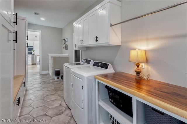 clothes washing area featuring washer and clothes dryer, a barn door, and cabinets