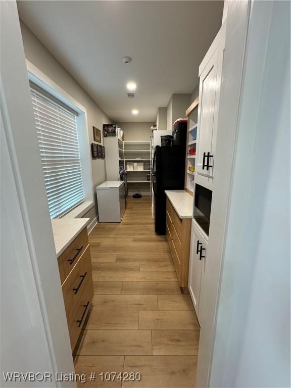 kitchen with light wood-type flooring and white cabinetry