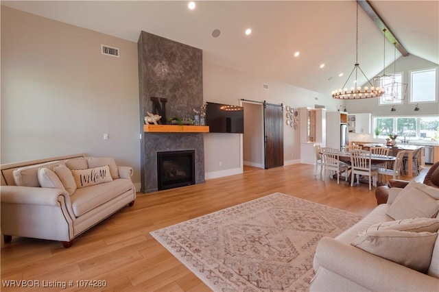 living room with a tile fireplace, high vaulted ceiling, a notable chandelier, beamed ceiling, and light hardwood / wood-style floors