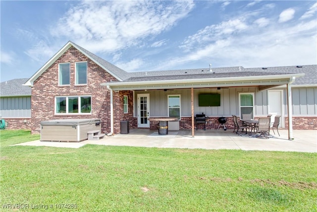 back of house with a yard, a patio, and a hot tub