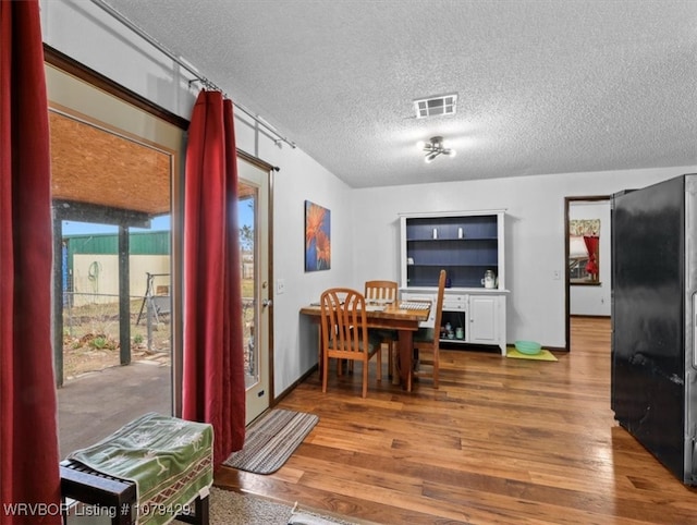 dining room featuring visible vents, a textured ceiling, and wood finished floors