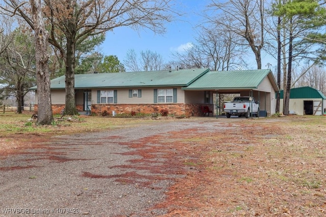 single story home with a carport, metal roof, brick siding, and dirt driveway