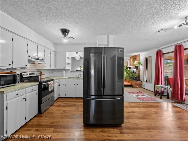 kitchen featuring under cabinet range hood, tasteful backsplash, stainless steel appliances, light countertops, and dark wood-style flooring