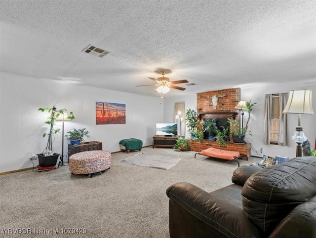 carpeted living area with visible vents, a textured ceiling, ceiling fan, and a fireplace