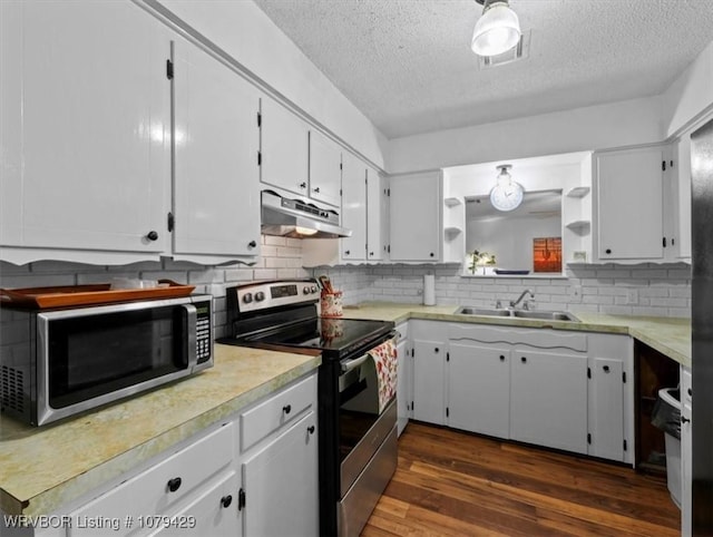 kitchen featuring under cabinet range hood, a sink, appliances with stainless steel finishes, light countertops, and dark wood-style flooring