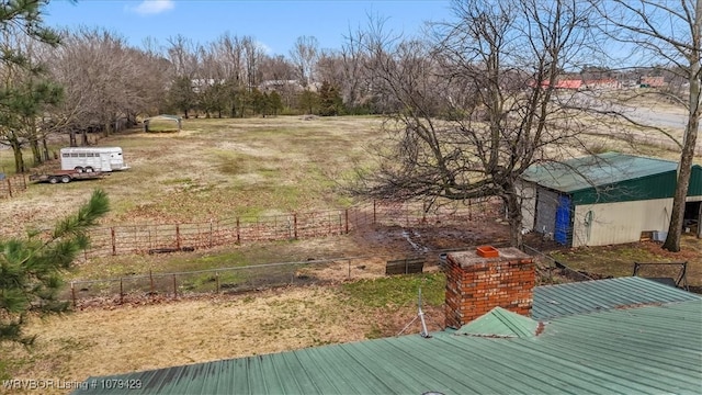 view of yard featuring an outbuilding, a rural view, and fence