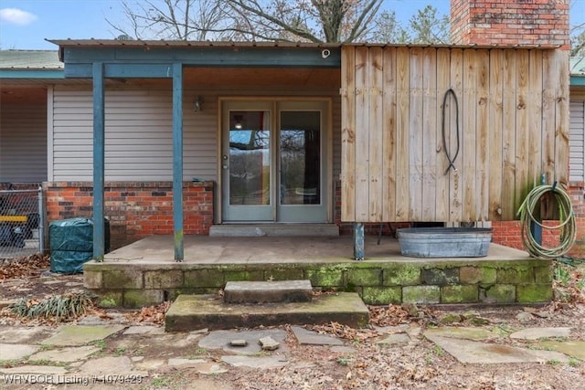 doorway to property featuring brick siding and fence