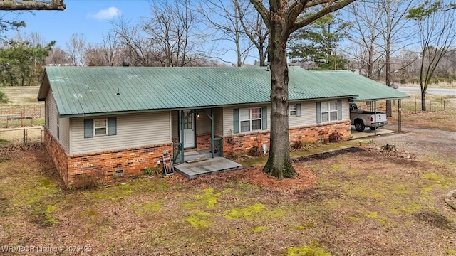 view of front of property with driveway, fence, metal roof, crawl space, and brick siding