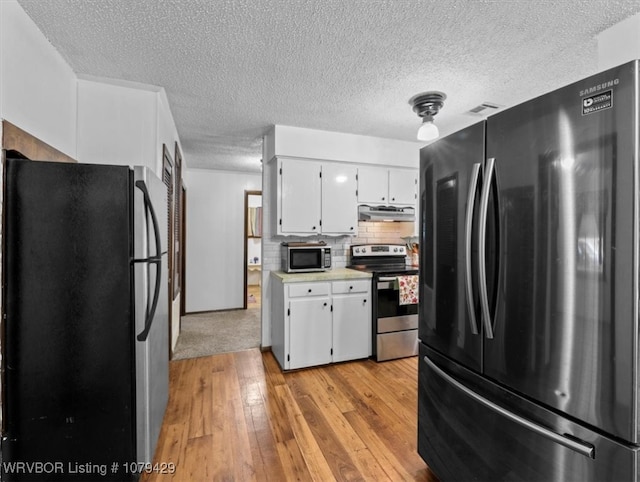 kitchen with light wood-style flooring, stainless steel appliances, light countertops, white cabinets, and under cabinet range hood