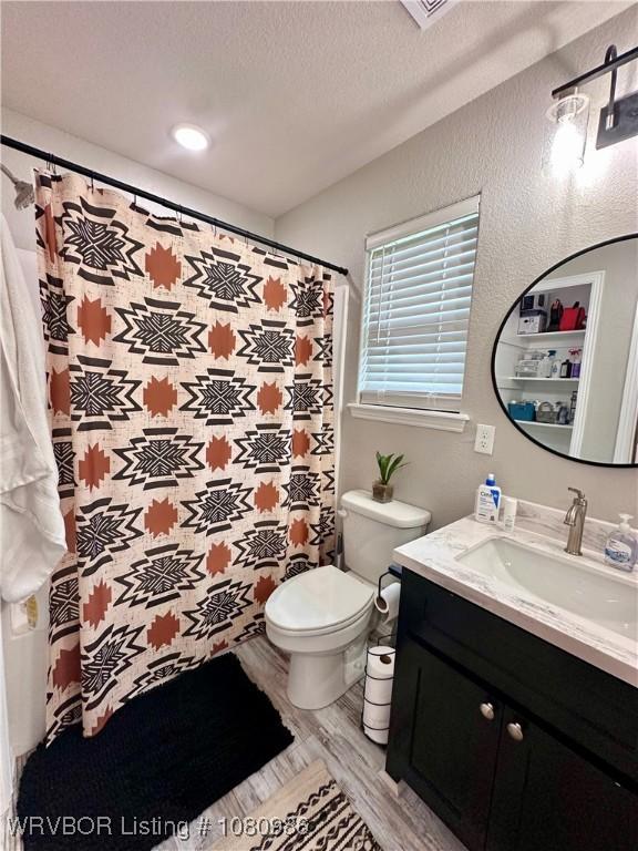 309 Arcadia Dr, Poteau, OK 74953 - bathroom with vanity, toilet, wood finished floors, and a textured ceiling