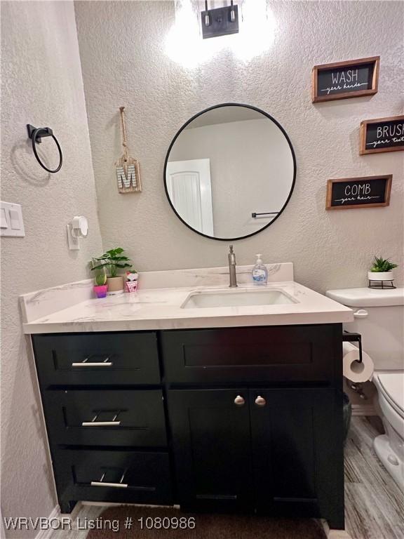 309 Arcadia Dr, Poteau, OK 74953 - bathroom with vanity, toilet, a textured wall, and wood finished floors