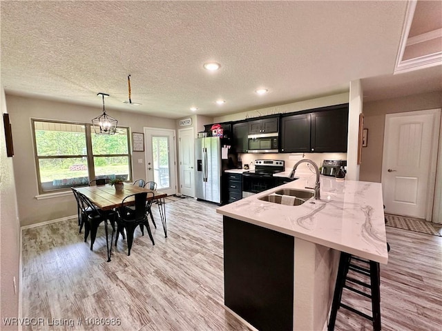309 Arcadia Dr, Poteau, OK 74953 - kitchen with appliances with stainless steel finishes, a sink, dark cabinets, light wood-style flooring, and a textured ceiling