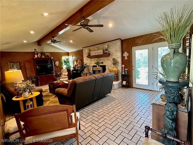 7434 N 217th Hwy, Charleston, AR 72933 - living room featuring wooden walls, a stone fireplace, healthy amount of natural light, ceiling fan, and a textured ceiling