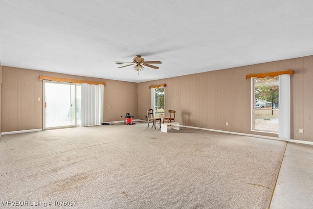 unfurnished room with carpet, ceiling fan, and wood walls