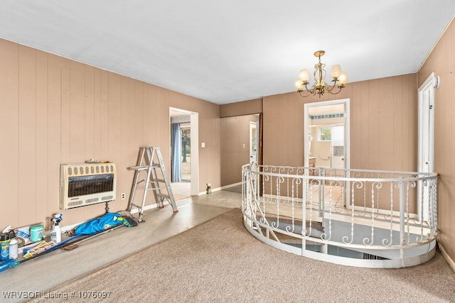 interior space featuring carpet, heating unit, a notable chandelier, and wood walls