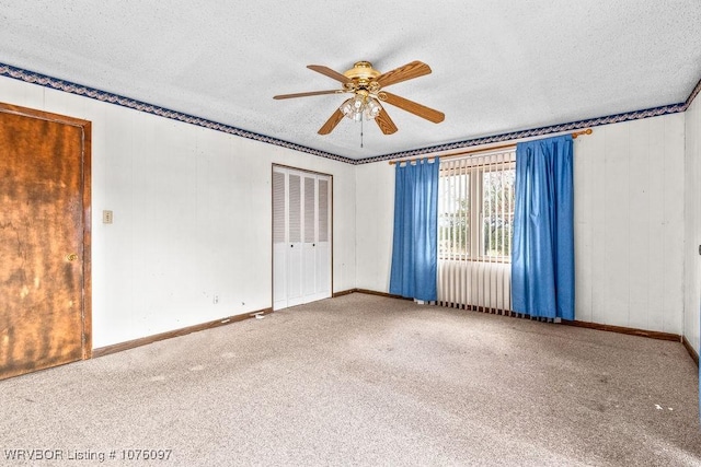 empty room featuring a textured ceiling, carpet floors, and ceiling fan