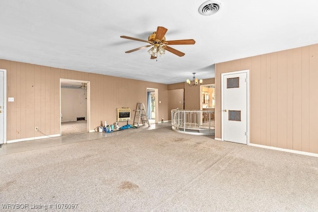 unfurnished living room featuring light carpet, ceiling fan with notable chandelier, and heating unit