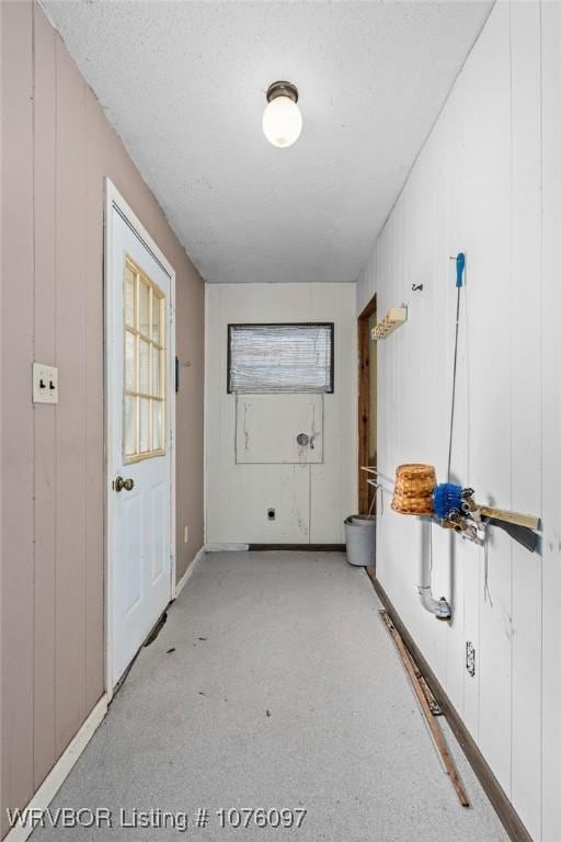 hallway with wood walls and a textured ceiling