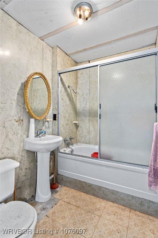 bathroom featuring tile patterned flooring, toilet, and enclosed tub / shower combo