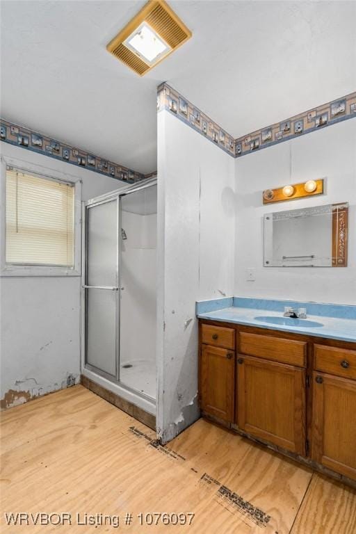 bathroom with hardwood / wood-style floors, vanity, and a shower with shower door