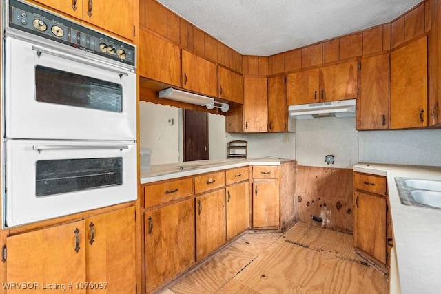 kitchen featuring sink, white double oven, and a textured ceiling