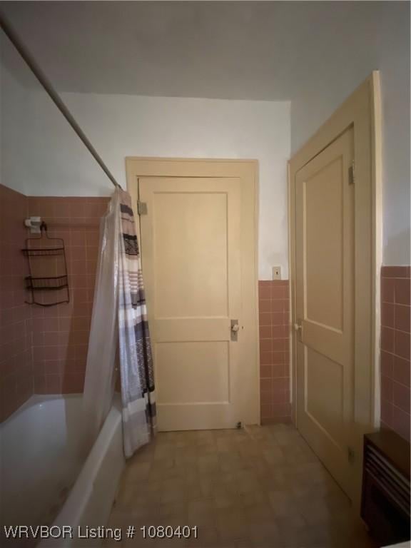 full bathroom with tile walls, a wainscoted wall, and shower / bath combo with shower curtain
