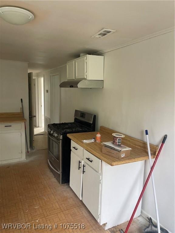 kitchen featuring light parquet floors, butcher block counters, white cabinetry, and stainless steel gas range